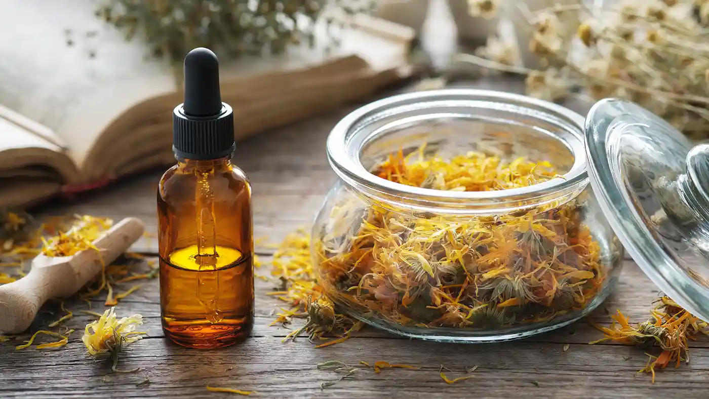 Dried Calendula flowers next to amber glass botttle