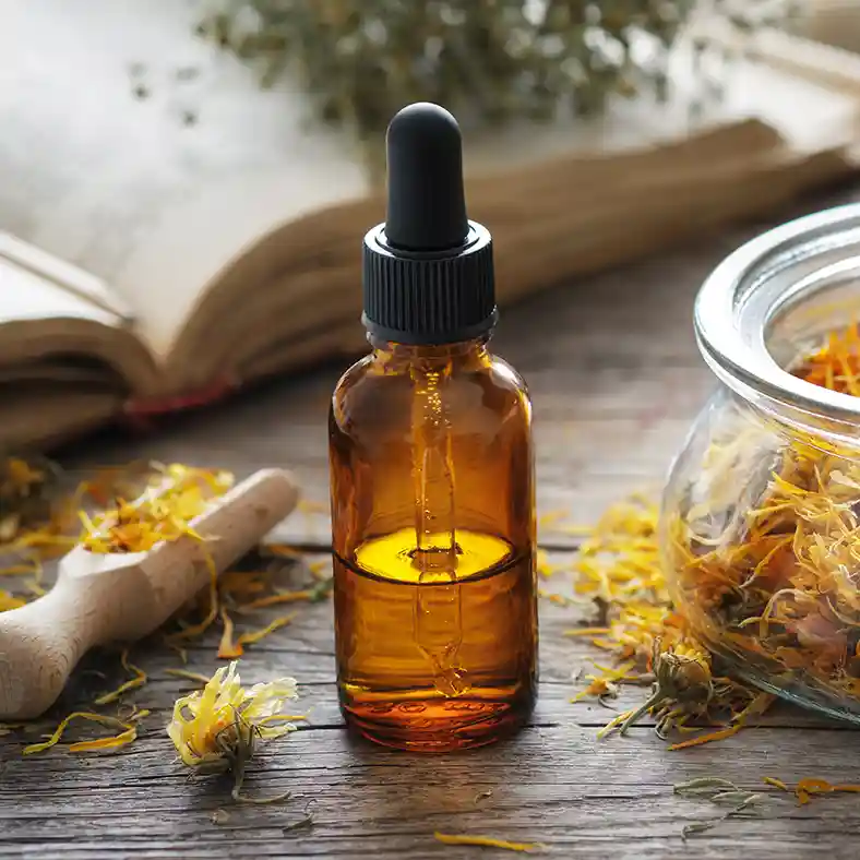 Dried Calendula flowers next to amber glass bottle